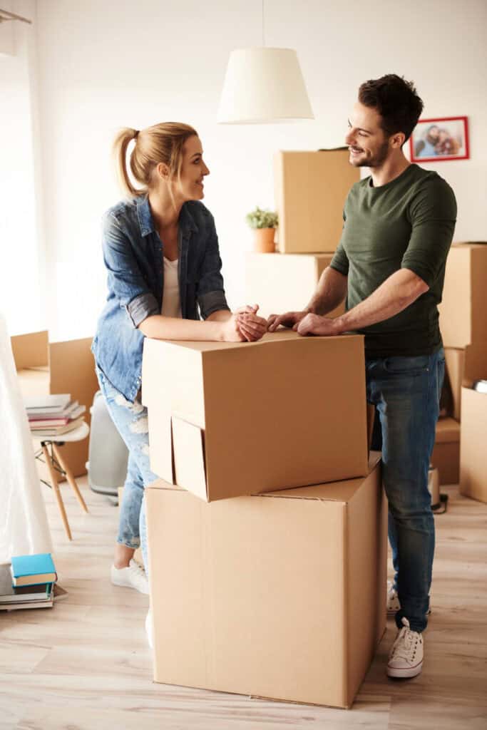 Relocation specialists having a conversation leaning on stacked up boxes