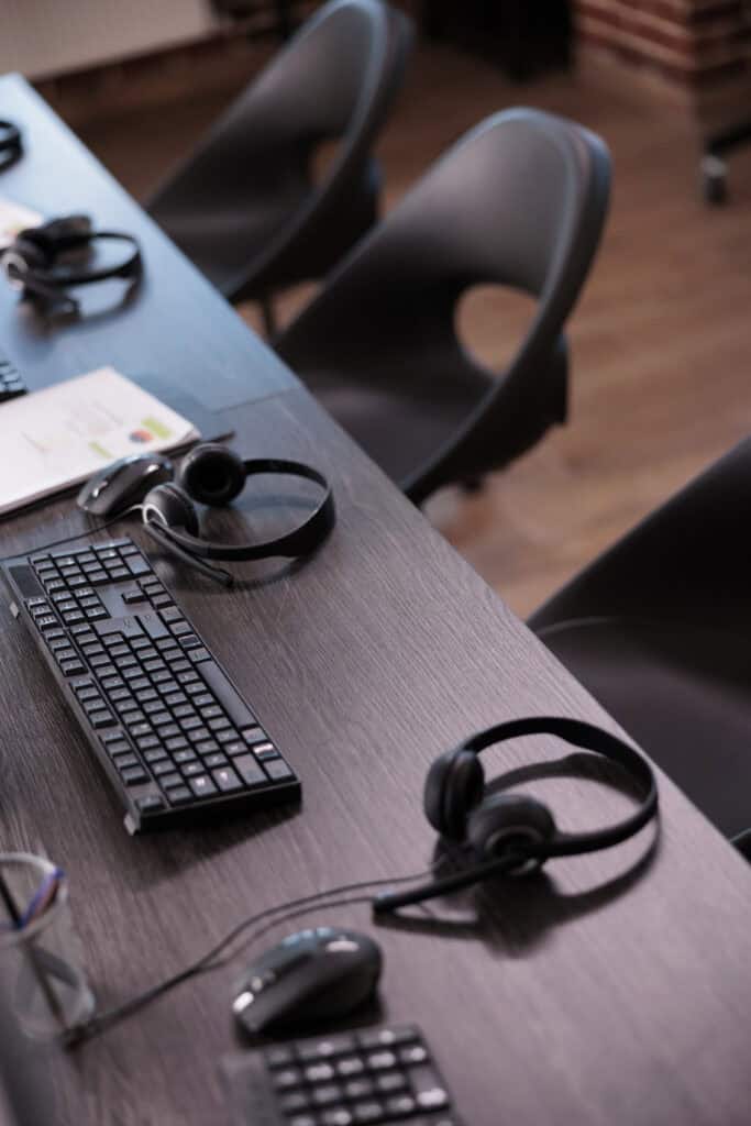 Empty helpdesk office with telephony equipment at reception to give assistance. No people in telemarketing space for customer service and client support, remote helpline headphones.