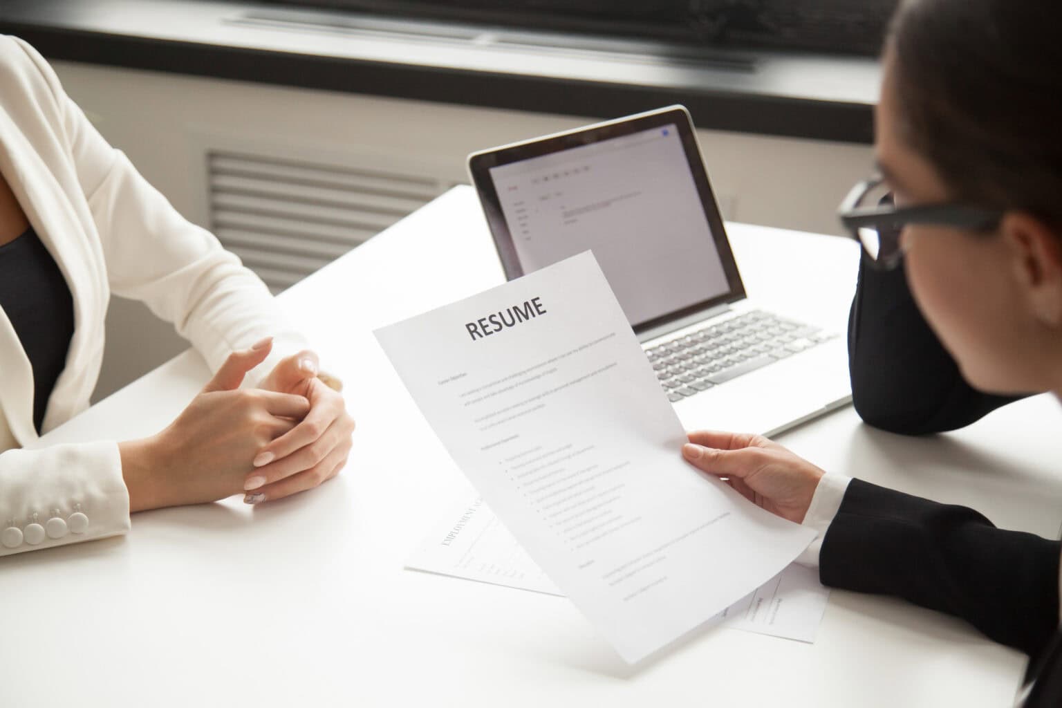 HR manager reading applicant resume while employee waits for questions