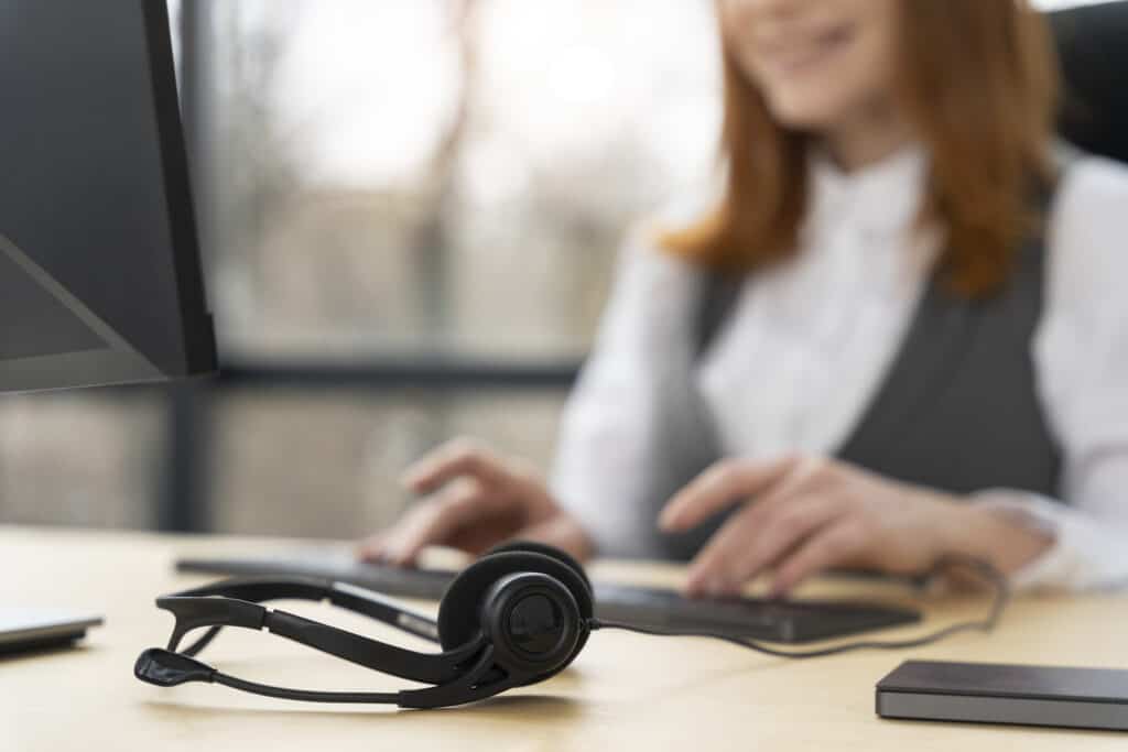Customer service expert working on computer with her headset on the table