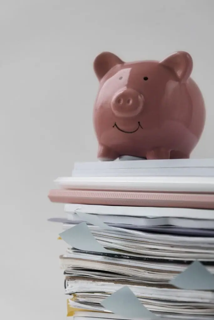 Pink piggy bank placed on top of stacked documents