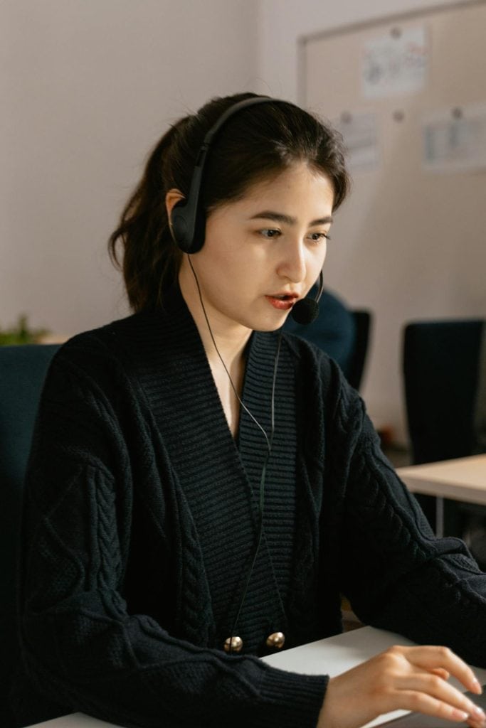 Customer contact professional sitting at her desk, talking to customer through the headset
