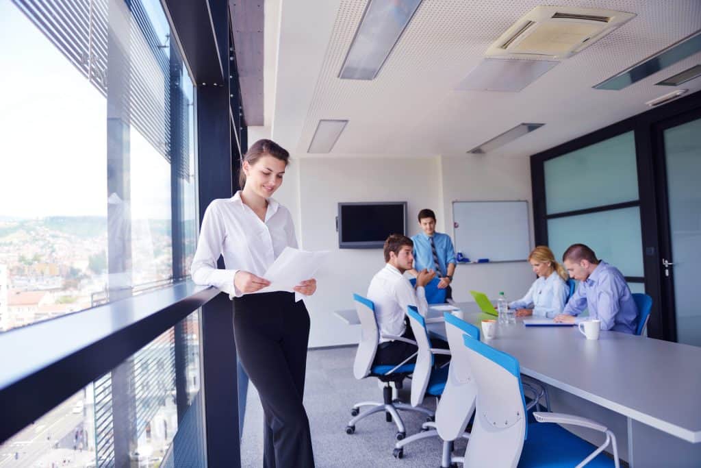 Business woman with her staff in background at modern bright office