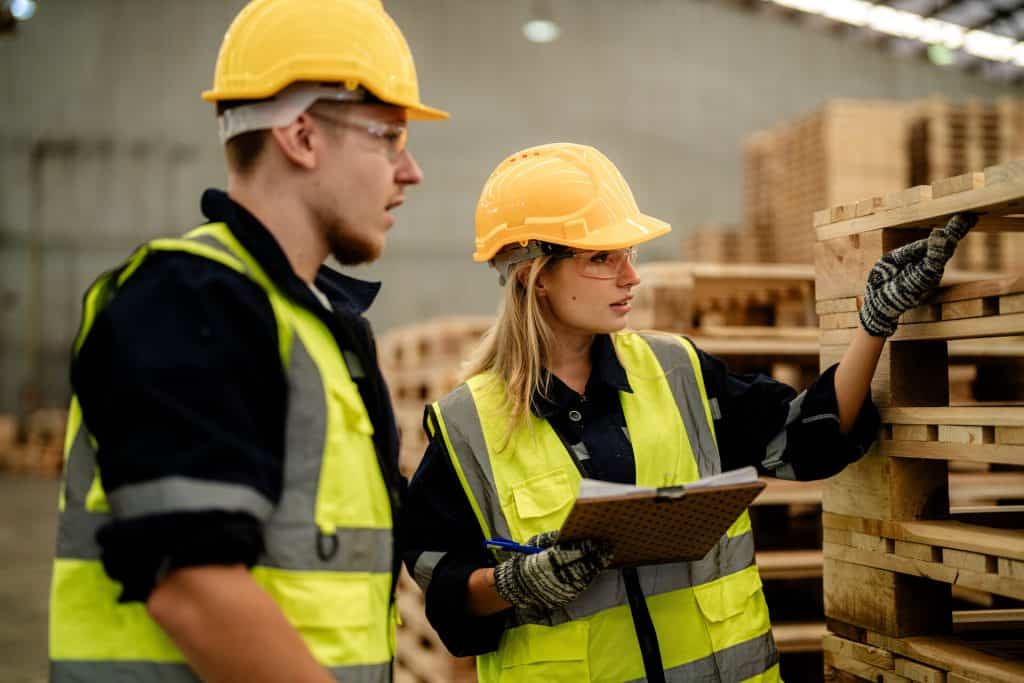 workers man and woman engineering walking and inspecting timbers wood in warehouse. Concept of smart industry worker operating. Wood factories produce wood palate.