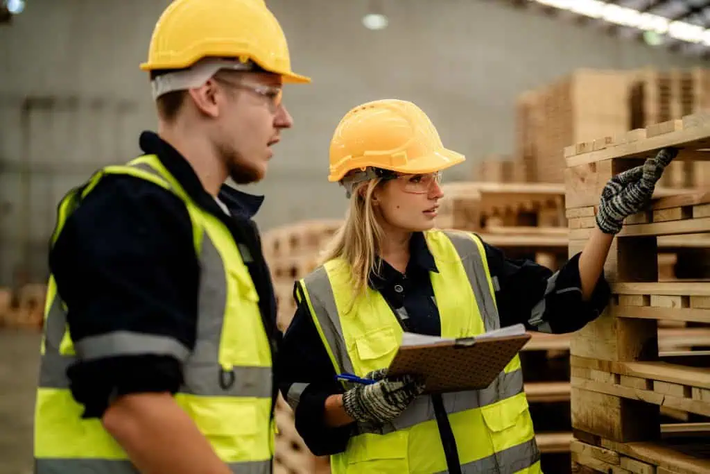 workers man and woman engineering walking and inspecting timbers wood in warehouse. Concept of smart industry worker operating. Wood factories produce wood palate.