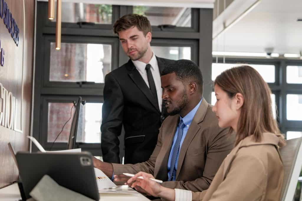 Three lean managers working in office, one man and woman sitting, the second man standing next to them